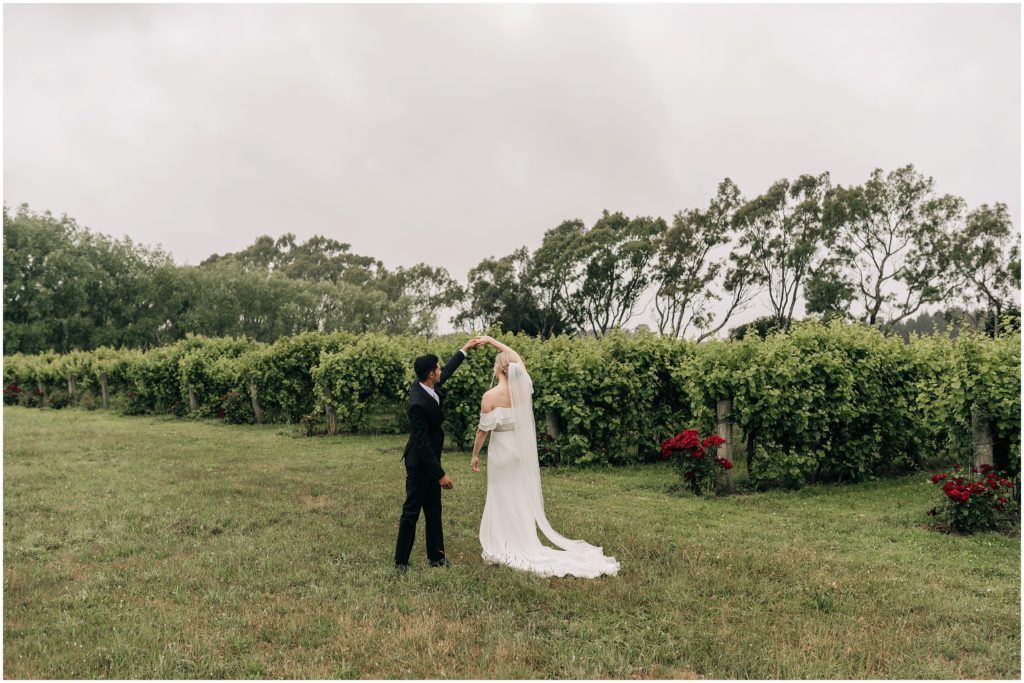 bride groom kissing white dress black suit vineyard trents christchurch wedding photographer green vines cloudy day summer