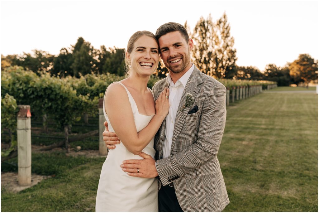 bride and groom smiling at camera vines sunset wither hills blenheim wedding new zealand emilia wickstead dress