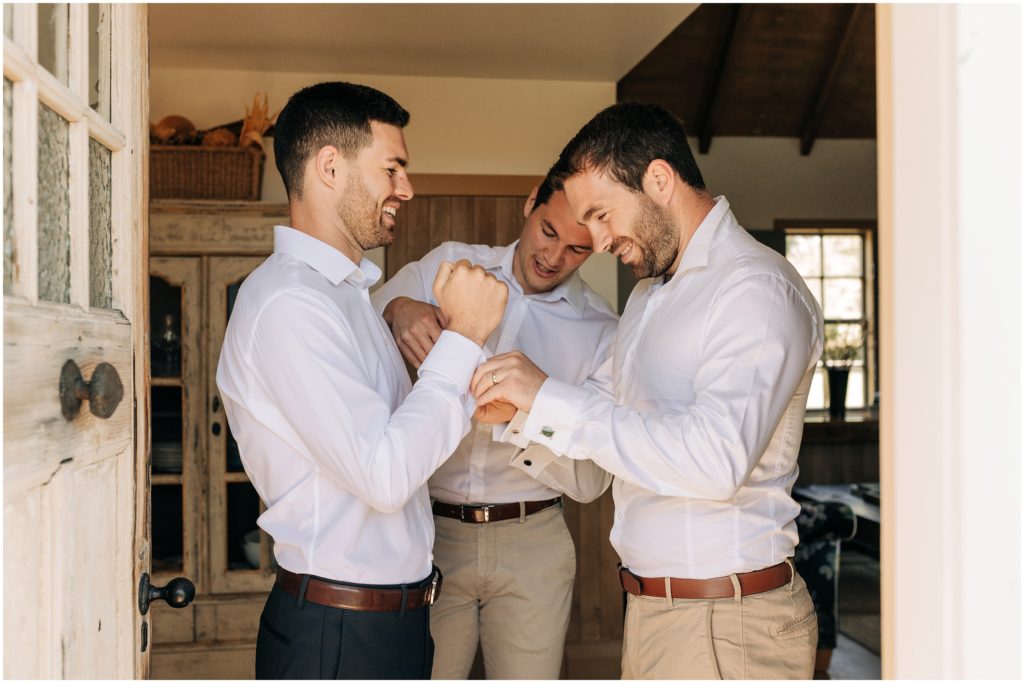 groomsmen helping groom cufflinks in doorway bell tower blenheim wedding photographer neutral palette
