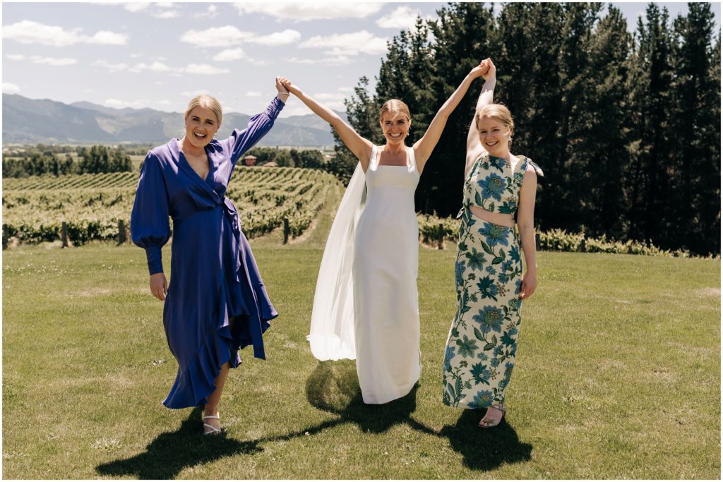 bride with two bridesmaids mismatched dog point wedding vineyard blenheim candid purple and green dresses