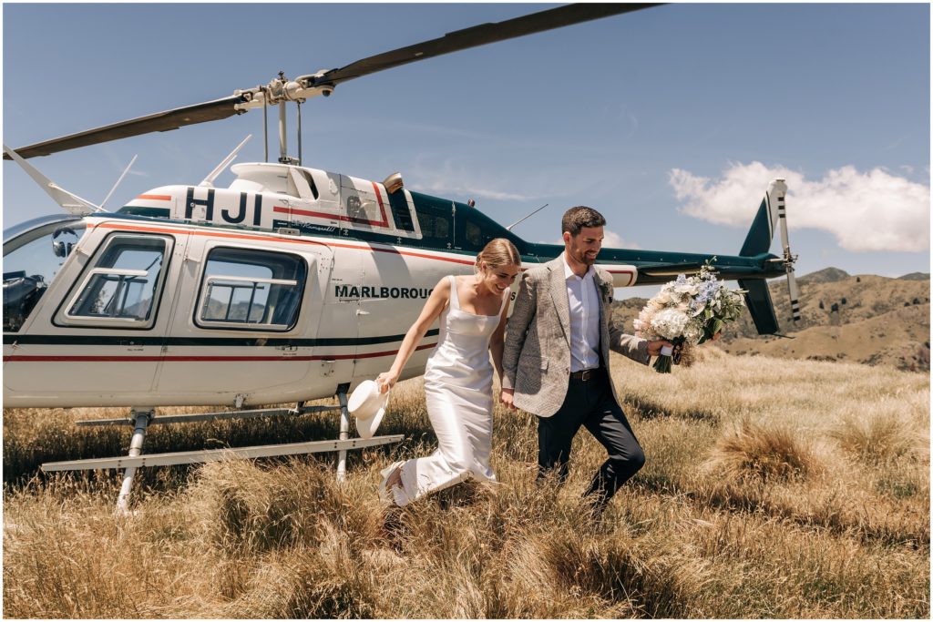 bride groom get out of helicopter dry brown grass wither hills blenheim wedding day photo spot sunny