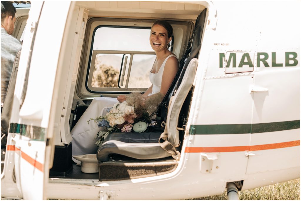 bride in marlborough blenheim helicopter wedding day bouquet on seat with headset smiling in dress