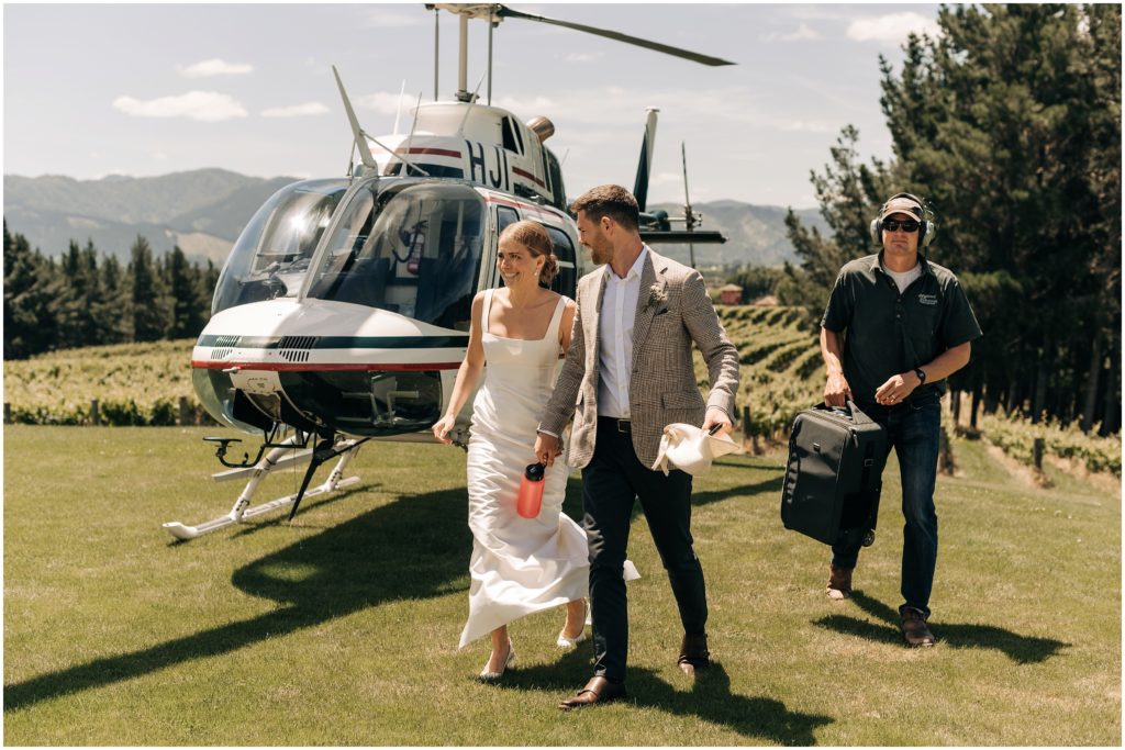 bride and groom walking from helicopter on wedding day at dog point vineyard in blenhem new zealand