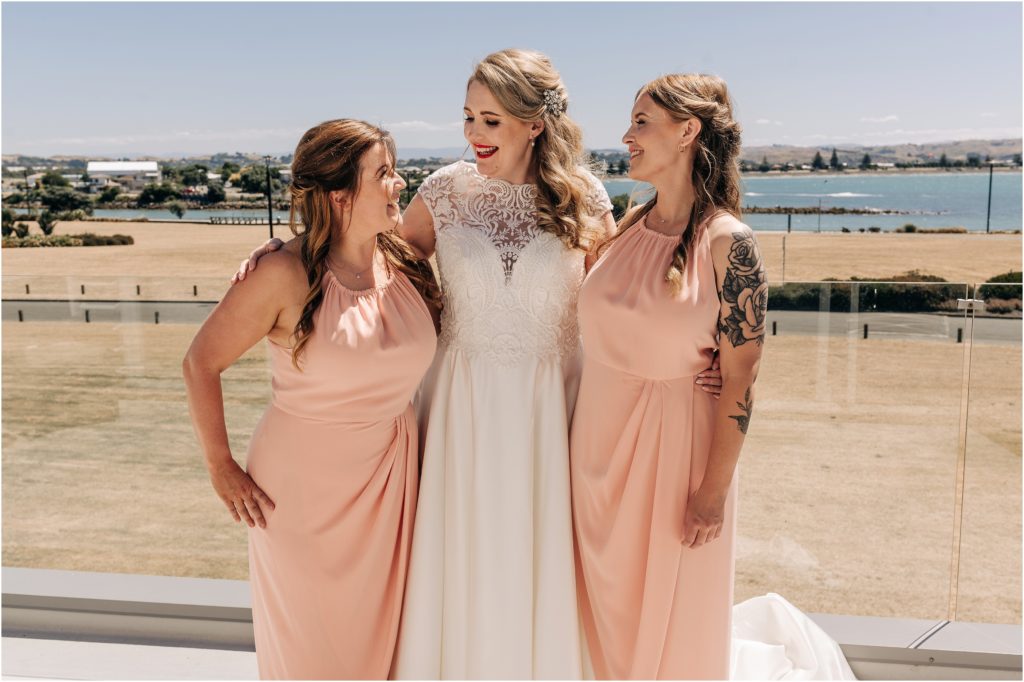 bride and bridesmaids in pink in napier new zealand sea view hotel getting ready sunny summer day wedding 
