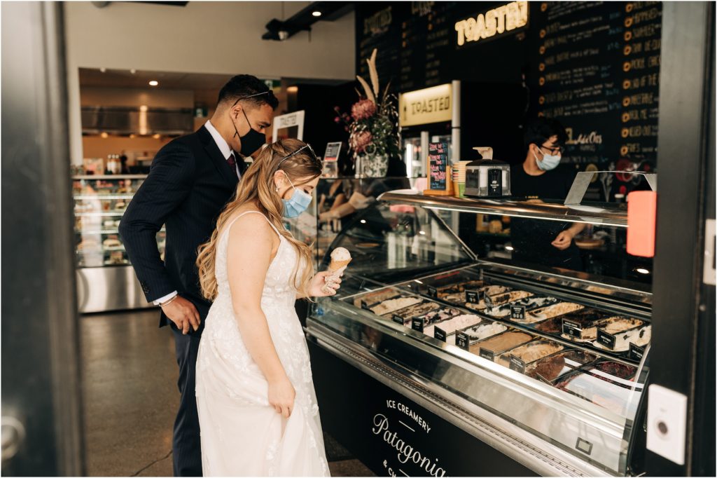 bride and groom choosing patagonia ice cream at toasted invercargill bagel shop wedding day in wedding dress with face mask
