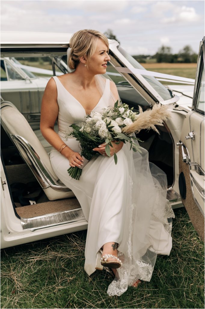 bride in white classic car with white flowers summer wedding christchurch nz