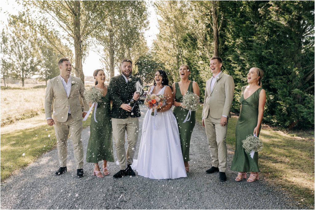 ellie haines loving ellies belly wedding photographer christchurch bridal party mi piaci green pink shaking champagne