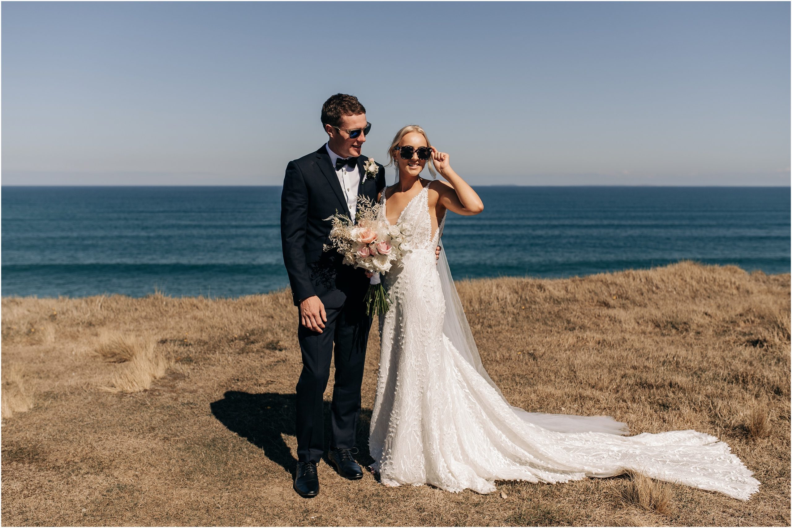 bride groom catlins fortrose cliffs with ocean in background new zealand elegant wearing sungalsses photographer