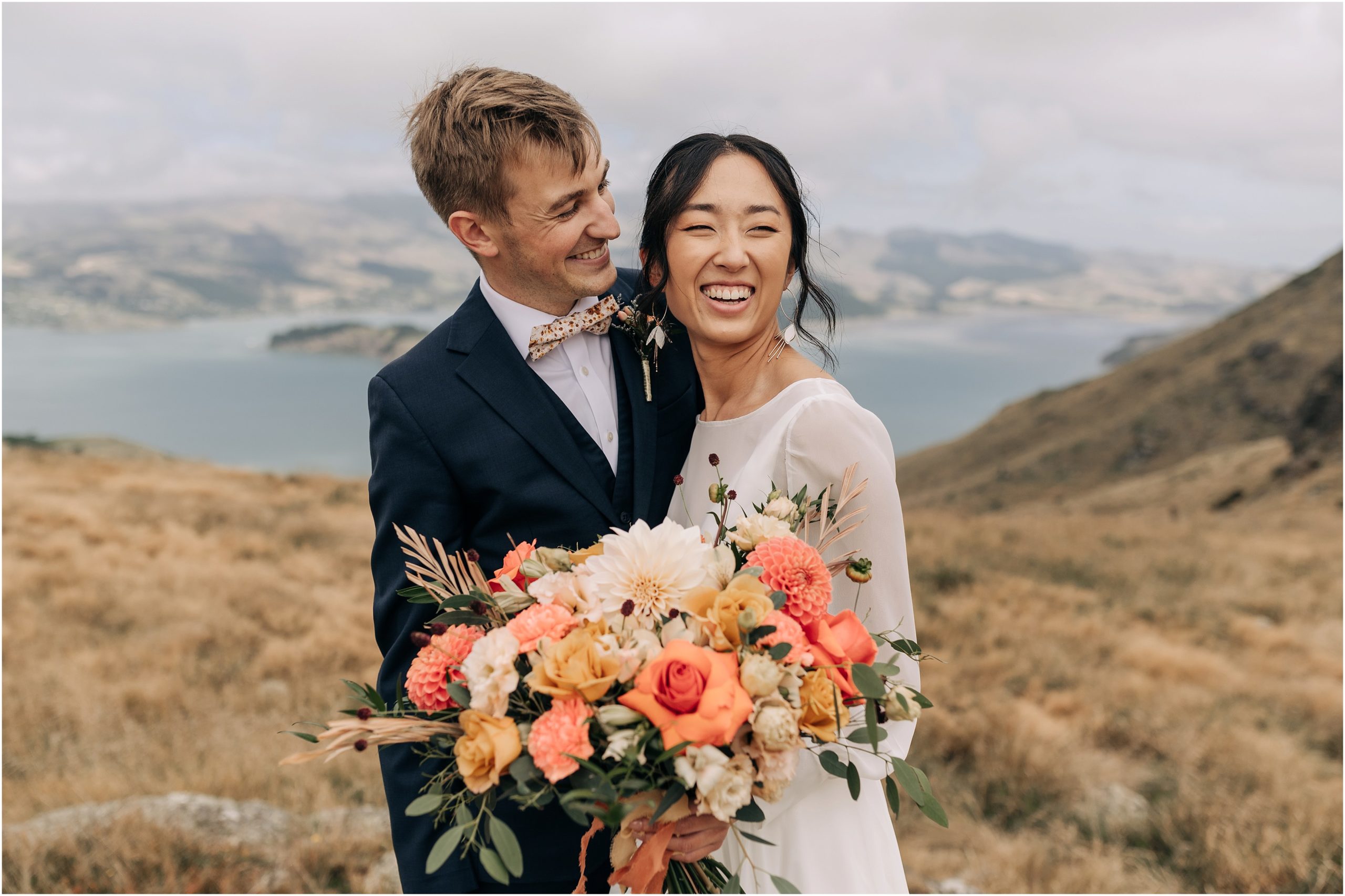 port hills christchurch wedding photography couple white dress orange flowers overcast day lyttelton harbour downies flowers caitlin wallace beth alice