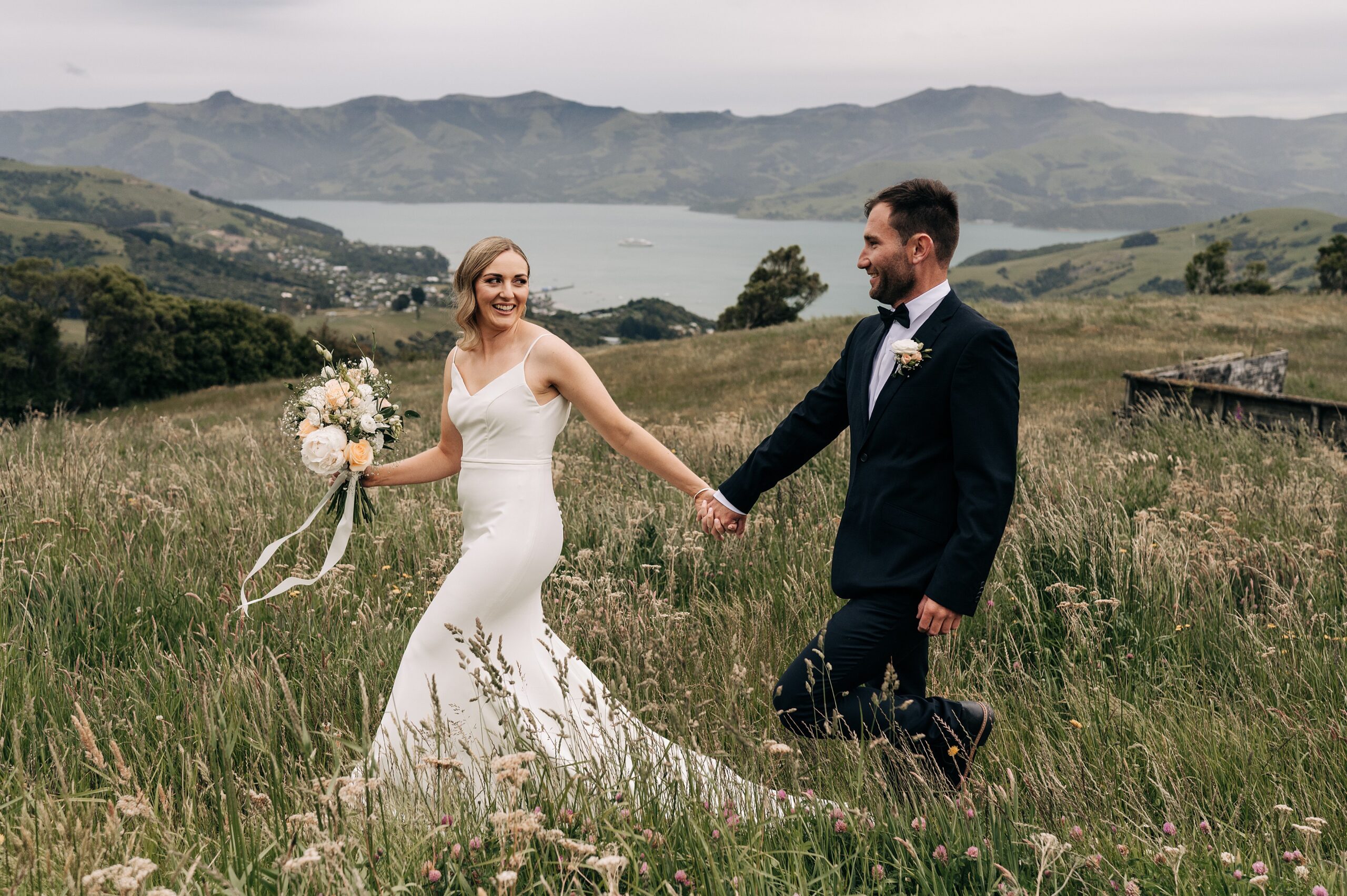bride and groom on their wedding day on mountaintop above akaroa harbour