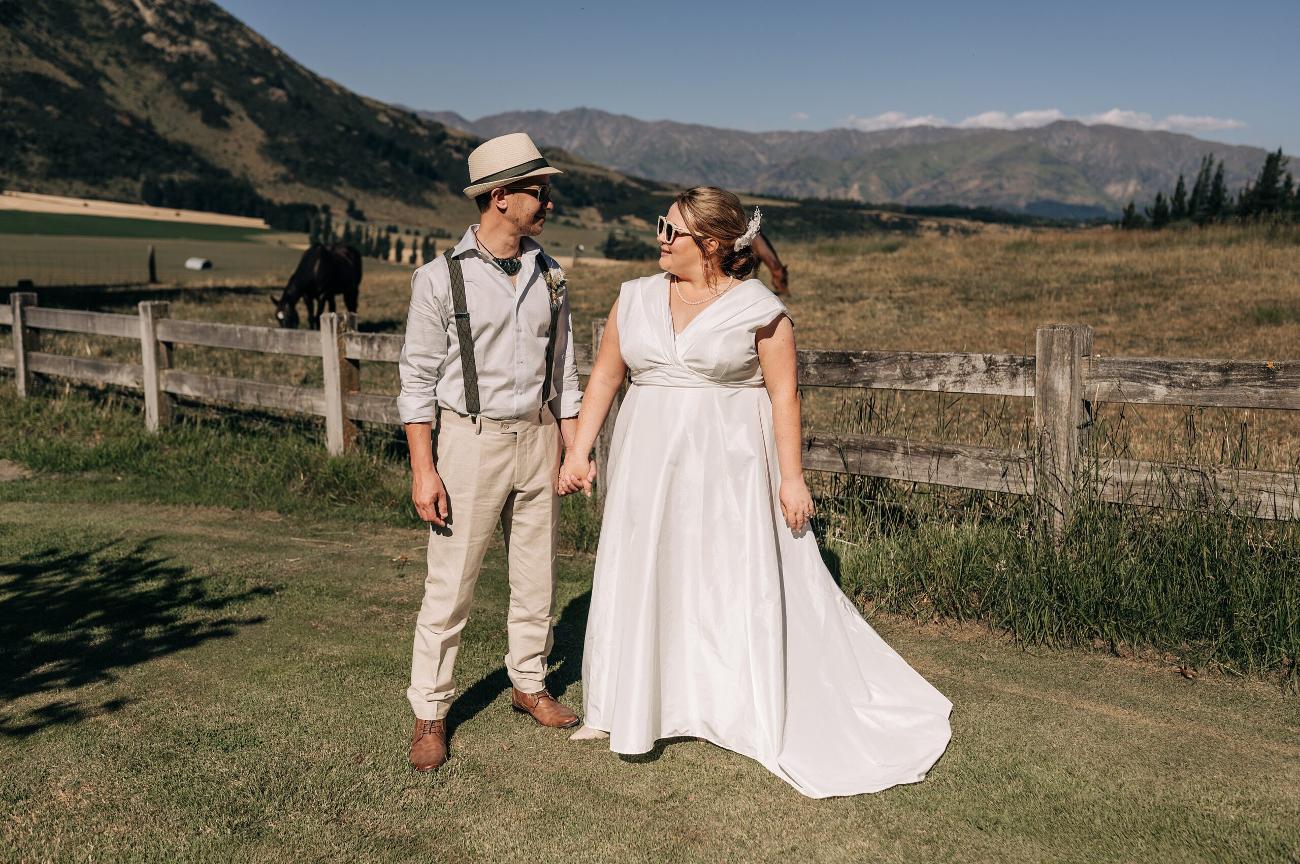 bride and groom in white sunglasses on a summer day in front of wanaka view at lookout lodge