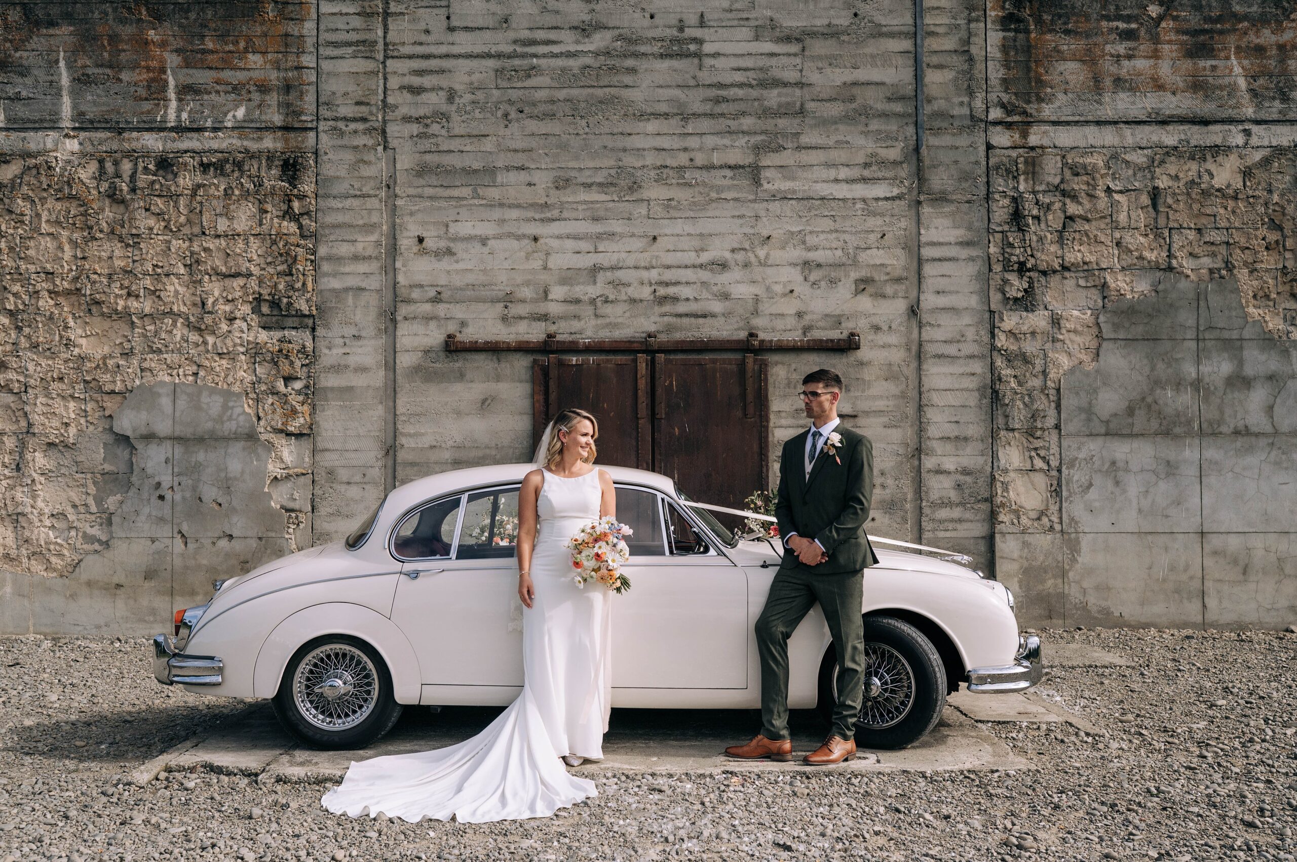 a bride and groom with white vintage car at their wedding at the flaxmill venue near christchurch